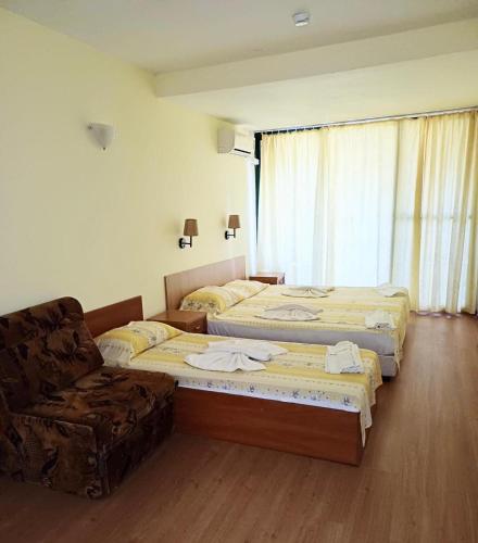 a hotel room with two beds and a chair at Hotel Nimfa-Rusalka in Sunny Beach