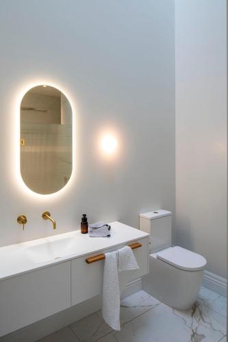 a white bathroom with a sink and a toilet at The Princes Apartment in Dunedin
