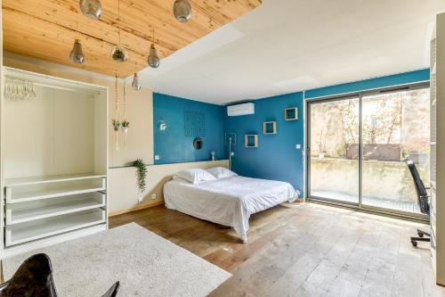 sypialnia z łóżkiem i niebieską ścianą w obiekcie Le Couvent des Ursulines - Penthouse climatisé piscine w mieście Narbona