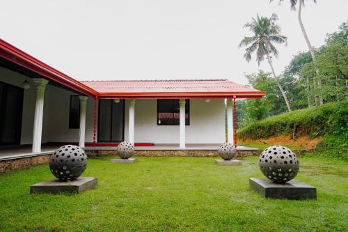 a house with three concrete spheres in the grass at Hyden Villa in Handapangoda