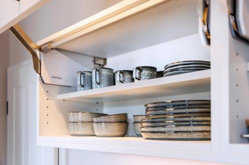 a pantry with plates and bowls on shelves at Logierhaus RheintorEins in Rees