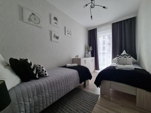 a bedroom with two beds and a window at Q Apart Meta -1, 2 lub 3-pokojowe, klimatyzowane apartamenty przy Manufakturze z garażem lub parkingiem Gratis, FV in Łódź