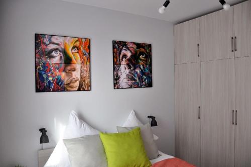 three paintings on the wall of a bedroom with a bed at Q Apart Meta -1, 2 lub 3-pokojowe, klimatyzowane apartamenty przy Manufakturze z garażem lub parkingiem Gratis, FV in Łódź
