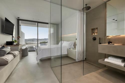 a bedroom with a bed and a glass wall at Domes White Coast Milos, Adults Only - Small Luxury Hotels of the World in Mytakas