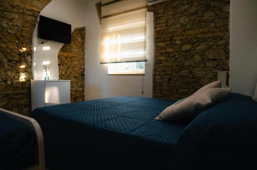 a bedroom with a blue bed with a stone wall at Al Mare Fuori in Calopezzati