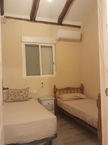 two beds in a room with a window at Casa rural Cerro Campón in Carmona