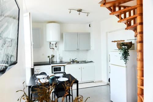 une cuisine avec des placards blancs et une table et des chaises noires dans l'établissement Barneville Plage, à Barneville-Carteret