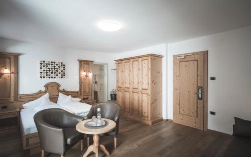 a hotel room with a bed and two chairs and a table at Hotel Alpenblick in Sesto