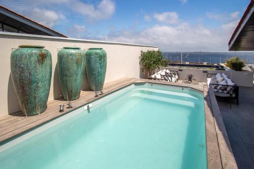 une piscine avec deux grands vases sur le côté d'un bâtiment dans l'établissement La Perle, à Marseillan