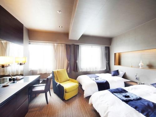 a hotel room with two beds and a desk at Silk Inn Kagoshima in Kagoshima