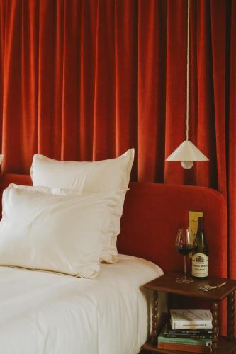 a bed with white pillows and a table with a lamp at Bellevigne Bourgogne in Chambolle-Musigny