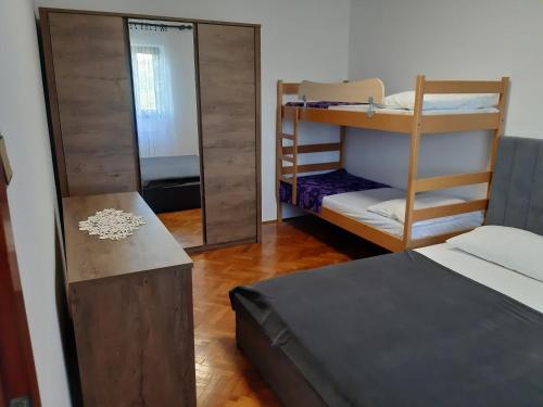 a room with two bunk beds and a mirror at Apartman Neda in Sveti Ivan Dobrinjski