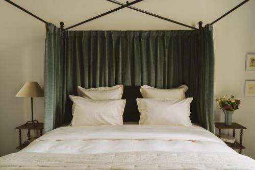 a large bed with green curtains and white pillows at Bellevigne Bourgogne in Chambolle-Musigny