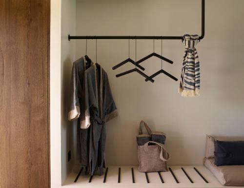 a room with a rack with coats and shoes at Domes White Coast Milos, Adults Only - Small Luxury Hotels of the World in Mytakas