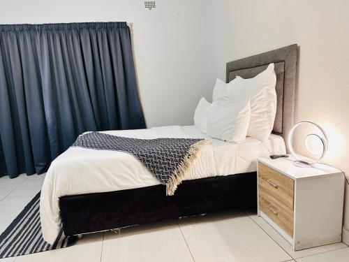 a bedroom with a bed with a mirror and a nightstand at House of Sharma in Bulawayo