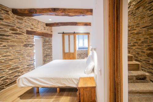 a bedroom with a bed and a stone wall at Apartamentos Lucio Rodinso in Castroverde