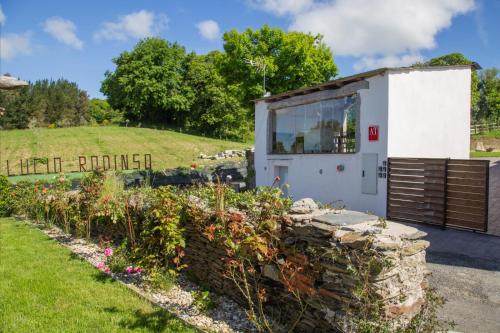 a small building with a window in a garden at Apartamentos Lucio Rodinso in Castroverde