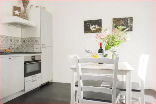 une cuisine blanche avec une table et des chaises blanches dans l'établissement Charmante maison Les Glycines DisneyLand Paris, à Montry