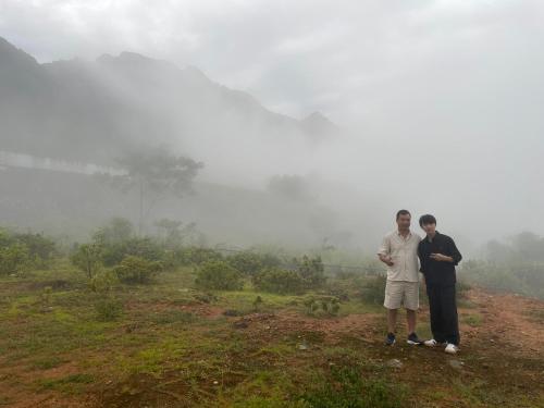 two men standing on a hill in the fog at Pù Luông Sala Homestay in Hương Bá Thước