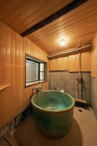 a bathroom with a large green tub in a room at 古民家リトルヴィラTokorangi 自然派オーガニックヴィラ 画像内の滞在時のお願いを必ずご確認お願いします in Tokoname