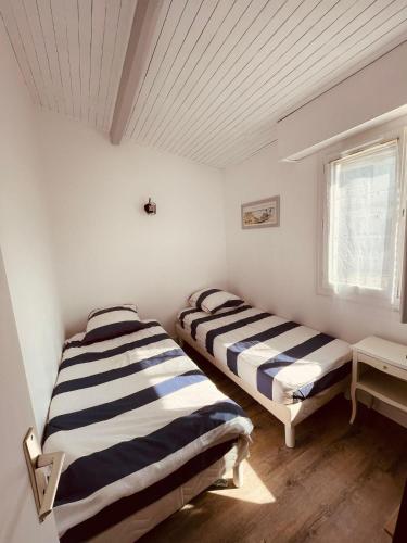 Ce lit se trouve dans un dortoir doté de murs blancs et d'une fenêtre. dans l'établissement L'Echo des Vagues, à Vieux-Boucau-les-Bains