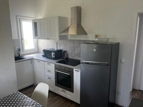 La cuisine est équipée d'un réfrigérateur noir et d'un four micro-ondes. dans l'établissement L'Echo des Vagues, à Vieux-Boucau-les-Bains