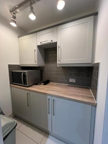 a kitchen with white cabinets and a microwave at Lovely Dublin Home - Just 15 Mins to City Centre in Dublin