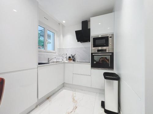 une cuisine blanche avec un évier et un micro-ondes dans l'établissement Résidence Lacour, à Cannes