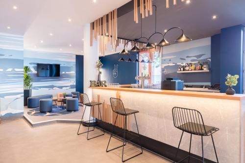 a bar in a restaurant with blue walls and stools at Holiday Inn - the niu, Stream Mönchengladbach by IHG in Mönchengladbach