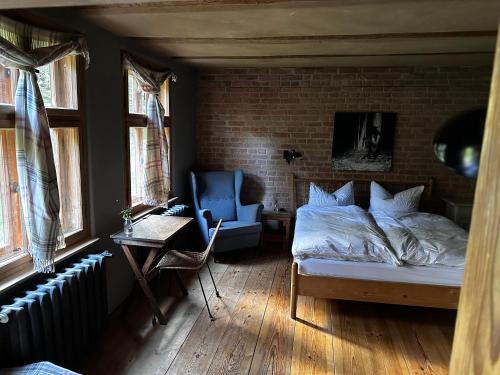 a bedroom with a bed and a chair and windows at Auszeit auf dem Land im Forsthaus Hohe Heide in Heiligengrabe