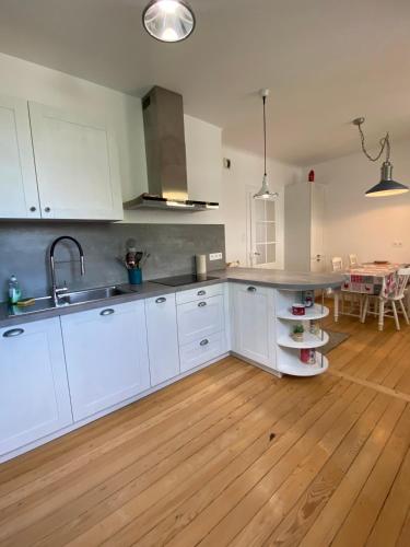 une cuisine avec des armoires blanches et un plancher en bois dans l'établissement BookingAlsace - Maison Mittelharth Parking Jardin, à Colmar