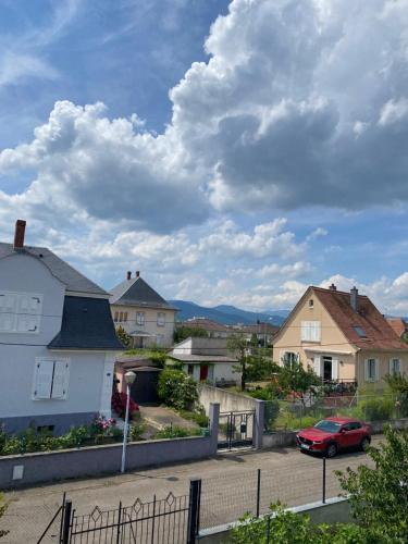 ein rotes Auto auf einem Parkplatz neben Häusern geparkt in der Unterkunft BookingAlsace - Maison Mittelharth Parking Jardin in Colmar