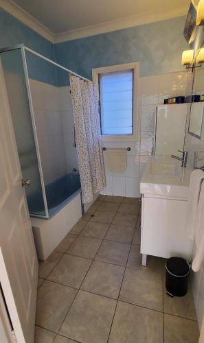 a bathroom with a tub and a sink and a shower at Coco's Cottage in Tamworth