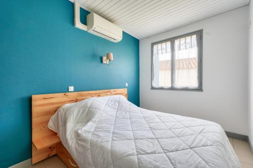 - une chambre avec un lit blanc et un mur bleu dans l'établissement Maison avec terrasse pour 5 - Calme et plage, à Longeville-sur-Mer
