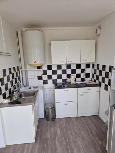 - une petite cuisine avec des armoires blanches et du carrelage noir et blanc dans l'établissement Location Studio meublé période Jeux Olympiques, à Rosny-sous-Bois
