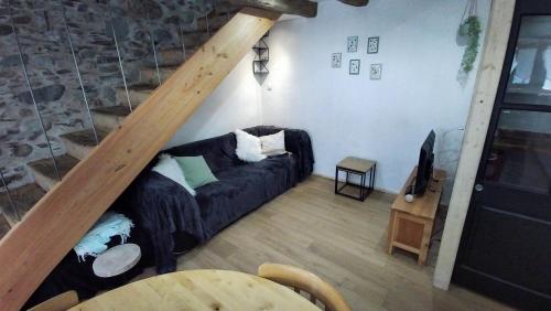 a living room with a black couch and a staircase at La maison verte in Arreau