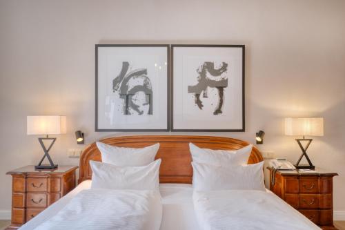 a bedroom with two beds and two lamps and two pictures at Hotel Eisenhut in Rothenburg ob der Tauber