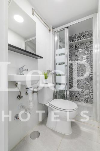 a white bathroom with a toilet and a shower at LooP America in Madrid