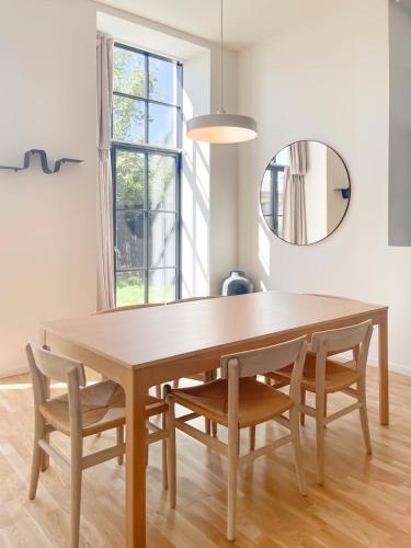 a dining room table with chairs and a mirror at Cozy and Bright Apartments with Private Car Park in Copenhagen
