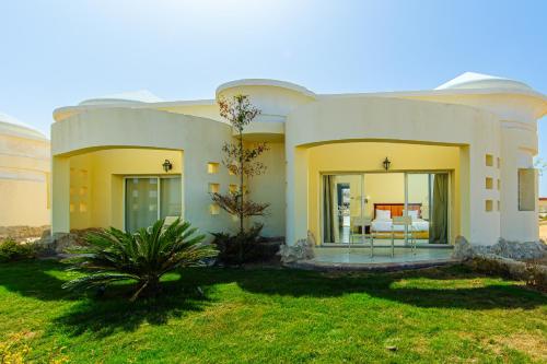 a large white house with a lawn in front of it at Siva Golden Bay Makadi in Hurghada
