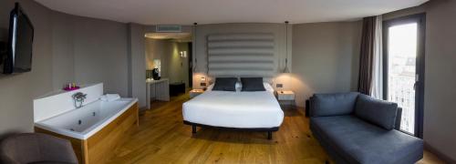 a bedroom with a bed and a couch and a tub at Zenit Vigo in Vigo