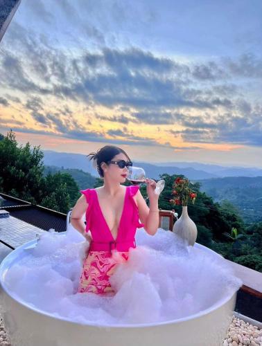 a woman is sitting in an inflatableonut bathtub drinking a glass of wine at Pool villa Doi Chang in Ban Huai Khai