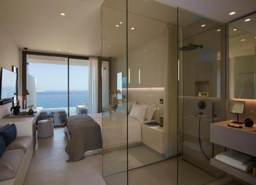 a hotel room with a bedroom with a glass wall at Domes White Coast Milos, Adults Only - Small Luxury Hotels of the World in Mytakas