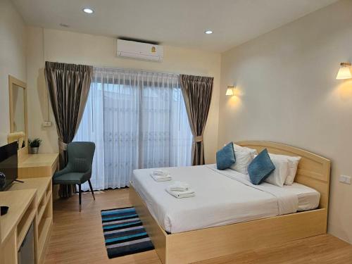 a bedroom with a bed and a desk and a window at Mercy Hostel in Chiang Rai