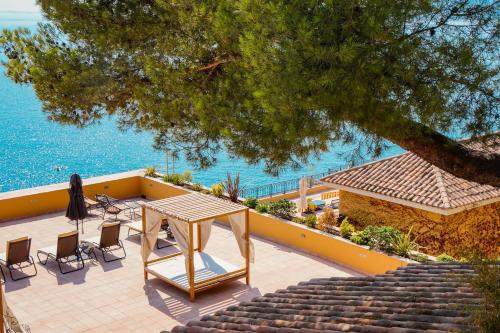 a patio with a table and chairs next to the water at Hôtel La Pérouse Nice Baie des Anges in Nice