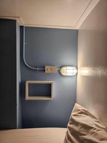 a bedroom with a blue wall with a bed and a mirror at Mercy Hostel in Chiang Rai