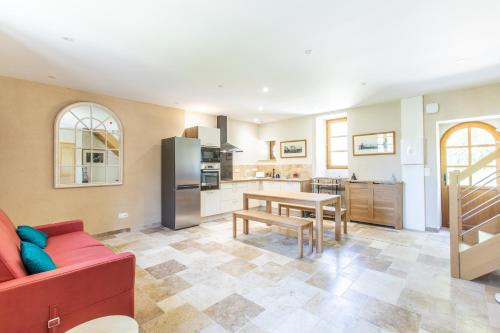 Il comprend une cuisine et un salon avec un canapé rouge et une table. dans l'établissement Châtea de Conon Gîte Cociergerie, à Cellettes