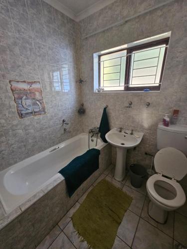 a bathroom with a tub and a toilet and a sink at Villa Rosseau in Freeland Park