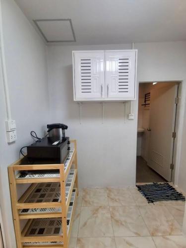 a kitchen with white cabinets and a pot on a shelf at Rainbow Bungalow Haadrin Koh Phangan in Haad Rin