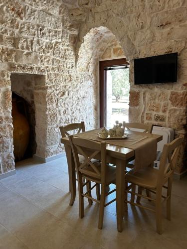 a dining room with a table and chairs and a stone wall at Il Trullo di Bina in Pezze di Greco